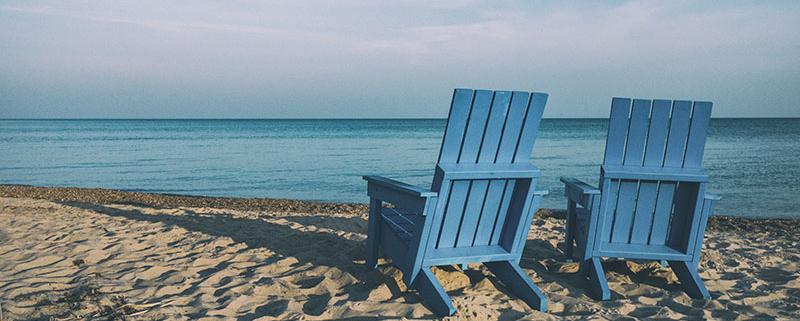 Two blue beach chairs on a sandy beach